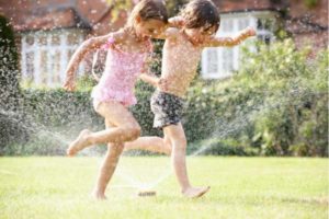 kids are playing with sprinklers 