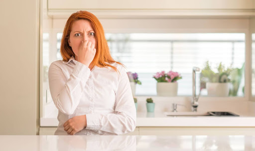 Homeowner holding nose because of stinky sink drain.